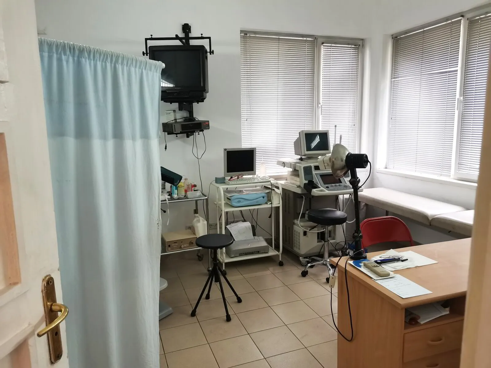 Кабинет за преглед в Клиника Акту, на снимката се вижда бюро, ехограф, малка съблекалня, монитор и лекарски апаратури.